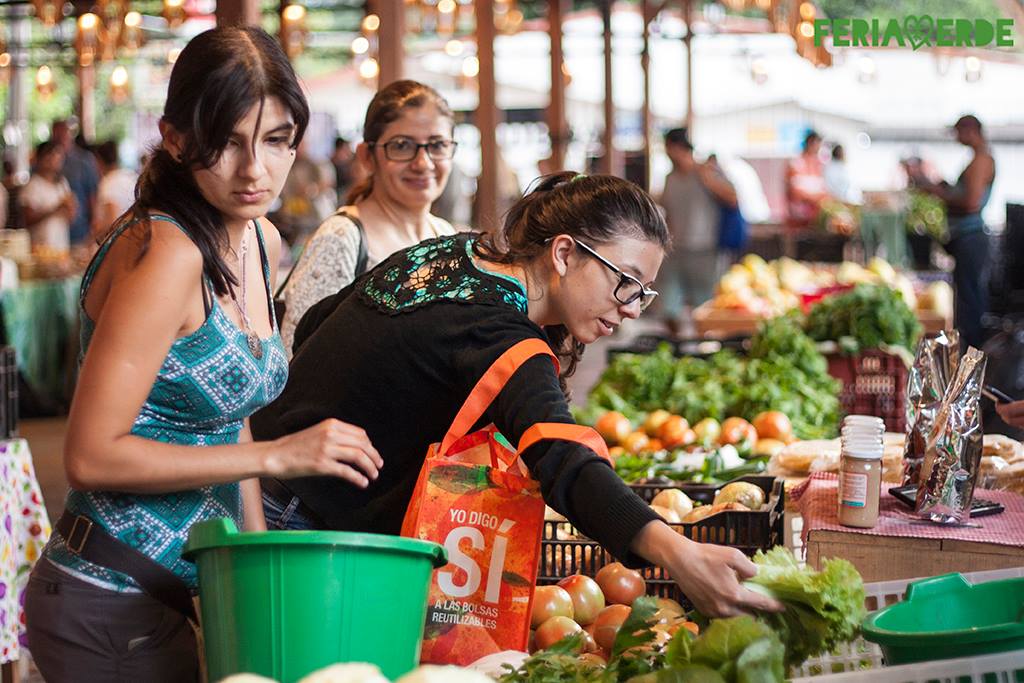 Personas eligiendo verduras en un puesto de Feria Verde de Aranjuez